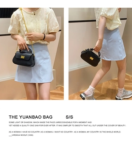 Detail view of the black leather Yuanbao bag with a gold metal clasp and elegant chain