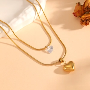Detail of double-layer snake chain with gold heart pendant and clear crystal heart charm