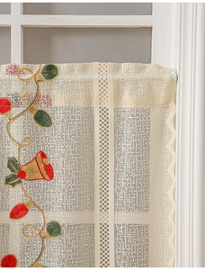 Detail of Christmas bell embroidery on cream lace curtain with festive light patterns