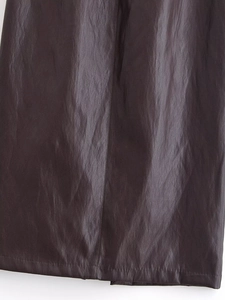 Gros plan sur la texture du similicuir marron foncé et les coutures de la jupe