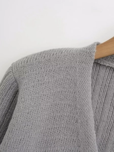 Close-up of grey knit sweater shoulder detail on a wooden hanger with fine texture