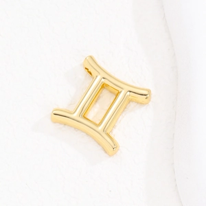 Macro shot of gold-plated Gemini zodiac pendant with a polished mirror finish surface