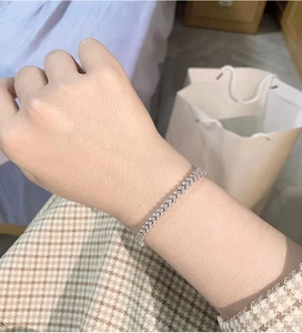 Close-up of a silver tennis bracelet with V-shaped diamond pattern on a woman's wrist