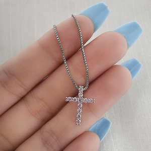 Macro view of silver cross pendant featuring shimmering pink zircons on a box chain