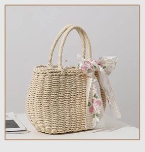 Detail of hand-woven straw bag with pink flower embroidery ribbon and circular handles