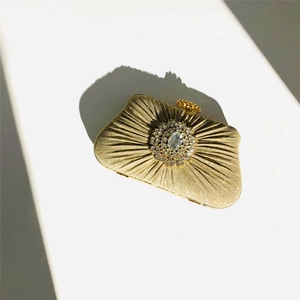 Top view of gold pleated evening clutch bag with sparkling central rhinestone decoration