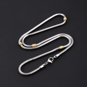 Silver Cuban link chain with gold beads and lobster clasp on black background