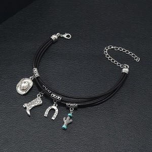 Close-up of leather bracelet featuring cowboy hat, boot, and Good Luck horseshoe charms