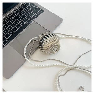 Macro detail of silver shell-shaped bag with pearl chain and metallic texture