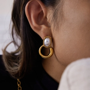Close-up of vintage gold hoop earring with large oval pearl on a female model's ear