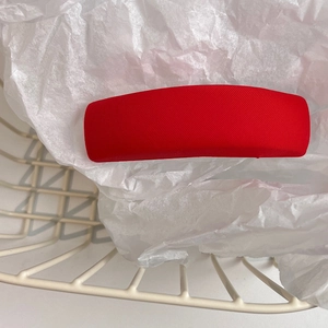 Detail shot of a red textured sponge hair clip on a white paper background with a metal basket