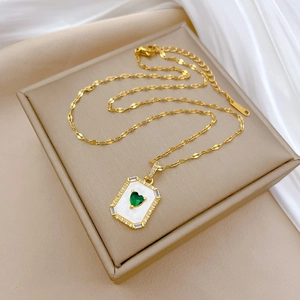 Detail of gold necklace featuring green heart gemstone and S925 engraving on clasp