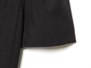Detailed macro view of black pleated dress fabric texture with fine stitching craftsmanship