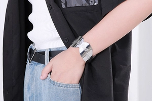 Detail of silver stainless steel open bangle with engraved paisley patterns on a wrist
