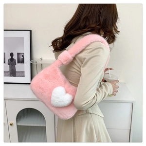 Chic pink plush shoulder bag with white 3D heart decor worn by a model in a cozy room