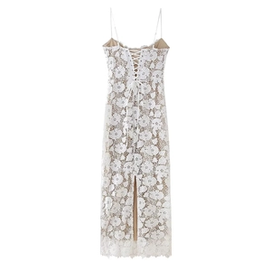 Détail de robe midi en dentelle blanche avec broderies florales et fines bretelles croisées