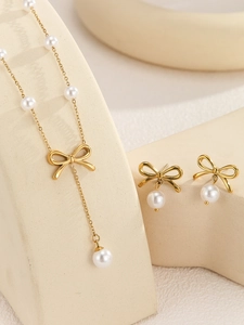 Detail of elegant gold bow jewelry set with lustrous white pearls on display