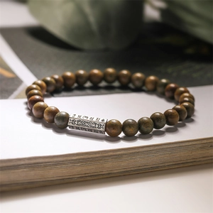 Gros plan de perles de bois brun foncé de 8 mm avec charme mantra en alliage