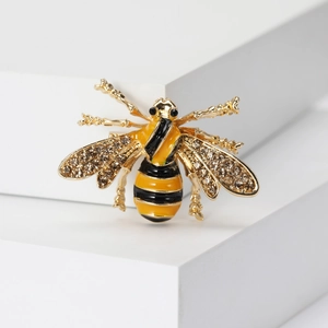 Macro detail of yellow enamel bee brooch with sparkling crystal wings on gold metal