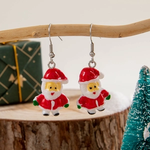Detailed view of Santa Claus resin drop earrings hanging on a festive Christmas tree branch