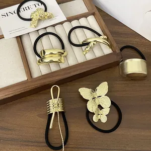 Detailed view of assorted gold alloy ponytail holders on an elegant wooden jewelry tray