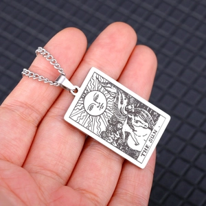 Detailed close-up of a silver stainless steel Tarot The Sun card pendant held in hand