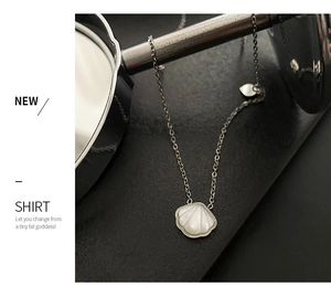 Detail of silver shell pendant necklace with heart charm and delicate chain link