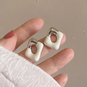 Detail of square hollow earrings held in hand showing silver and beige resin finish