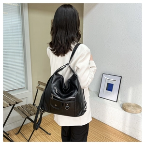 Rear view of a model wearing the black leather multi-pocket crossbody bag in a cafe