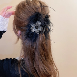 Vue détaillée de la pince à cheveux avec plumes noires et fleurs en strass sur modèle