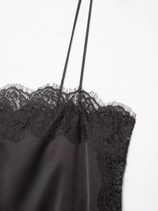 Détail d'un top en satin noir avec bordure en dentelle cil et fines bretelles réglables
