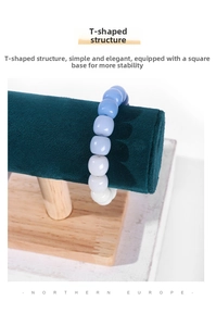 Detail of gradient blue beaded bracelet hanging on a dark green velvet T-bar jewelry stand