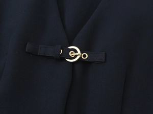 Detail of black crepe fabric with polished gold metal buckle and adjustable strap
