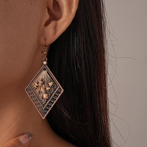 Detail of vintage bronze rhombus earrings with coconut beads on a model's ear