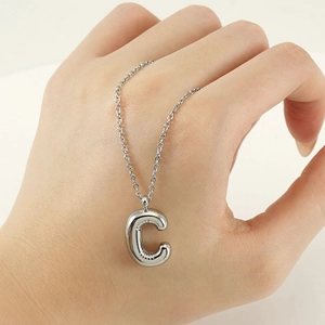 Close-up of polished silver bubble letter C pendant on a delicate stainless steel chain