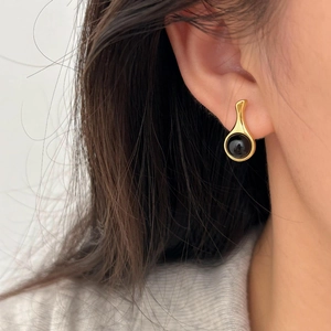 Minimalist gold teardrop earrings with round black onyx stones worn on ear