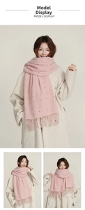 Detailed view of pink knitted scarf with colorful polka dots and long tassel trim