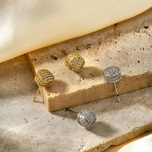 Sparkling square zircon stud earrings in gold and silver plating on stone background