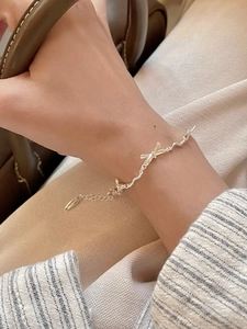 Detail of a wavy stainless steel bow bracelet with an adjustable extension chain