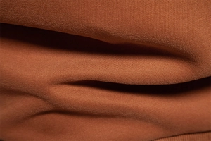 Macro detail of the premium soft brushed cotton fabric texture in rust brown color