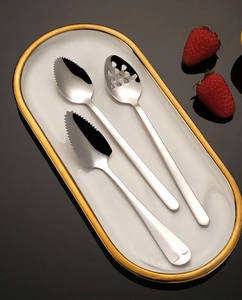 Three-piece stainless steel baby food spoons set with serrated edges on a tray