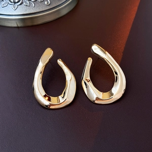 Macro detail of gold U-shaped geometric earrings on premium dark textured background