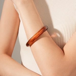 Detailed view of an amber resin bangle with a translucent texture on a model's wrist