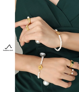 Baroque pearl bracelet with gold flower OT toggle and green gemstone ring on model