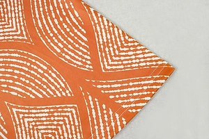 Close-up of double-needle hem on orange dress with white geometric dot pattern