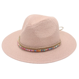 Close-up of pink straw Panama hat featuring colorful bead accessories and woven texture