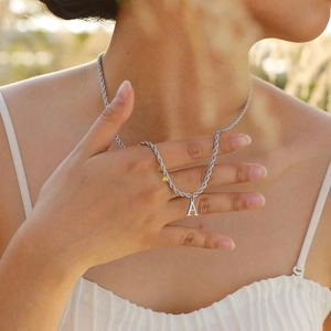 Close-up of letter A pendant on a silver twist rope chain worn by a female model