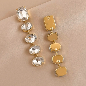 Elegant geometric gold earrings with square and oval crystals on champagne silk background