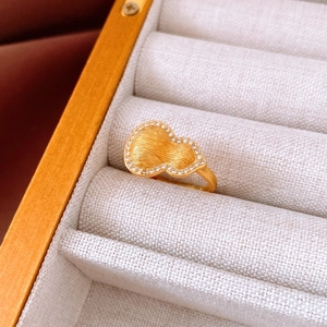 Macro detail of a golden gourd ring with brushed finish and zircon pavé on jewelry box