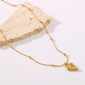 Gold heart pendant necklace with beaded titanium steel chain on stone, 18K gold plated